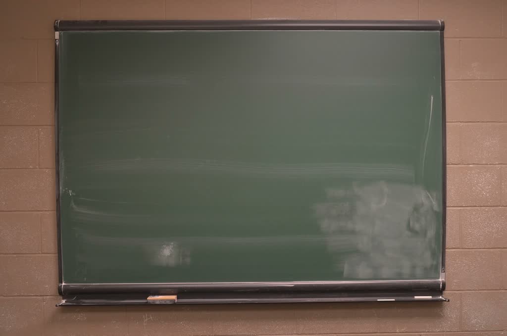 An empty classroom blackboard on a brick wall